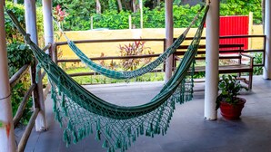 A hammock under a wooden pergola, with a bench and potted plant nearby. - Pousada Pêlo De Imbassai (Mata de São João)