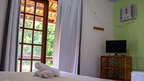 A hotel room with a bed, a television on a wooden stand, and a window with curtains. - Pousada Pêlo De Imbassai (Mata de São João)
