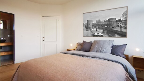 Ein Schlafzimmer mit einem Bett, Kissen, einem Nachttisch, einem Holzschrank und einer Tür.