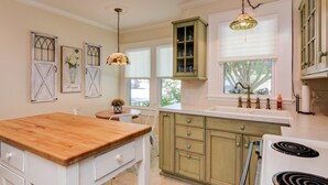 Una cocina con encimera de madera, armarios verdes y estufa blanca.