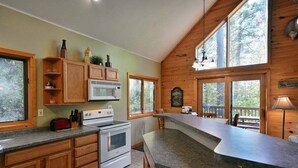 A kitchen with wooden cabinets, a microwave, a stove, and a large island counter. - Deer Trail Log Home #13  on Lake Delta near Iron River, WI (Iron River)