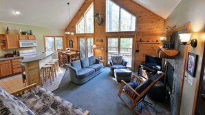 A spacious loft-style living area with a kitchen, dining area, and seating space. - Deer Trail Log Home #13  on Lake Delta near Iron River, WI (Iron River)