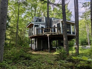 A two-story cabin with a deck, surrounded by a forest. - Acadia Treehouse near Bar Harbor - Private Luxury (Hancock)