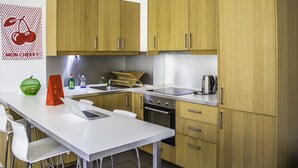 Eine moderne Küche mit Holzschränken, einer weißen Arbeitsplatte, einem Edelstahl-Spülbecken und einem eingebauten Backofen.