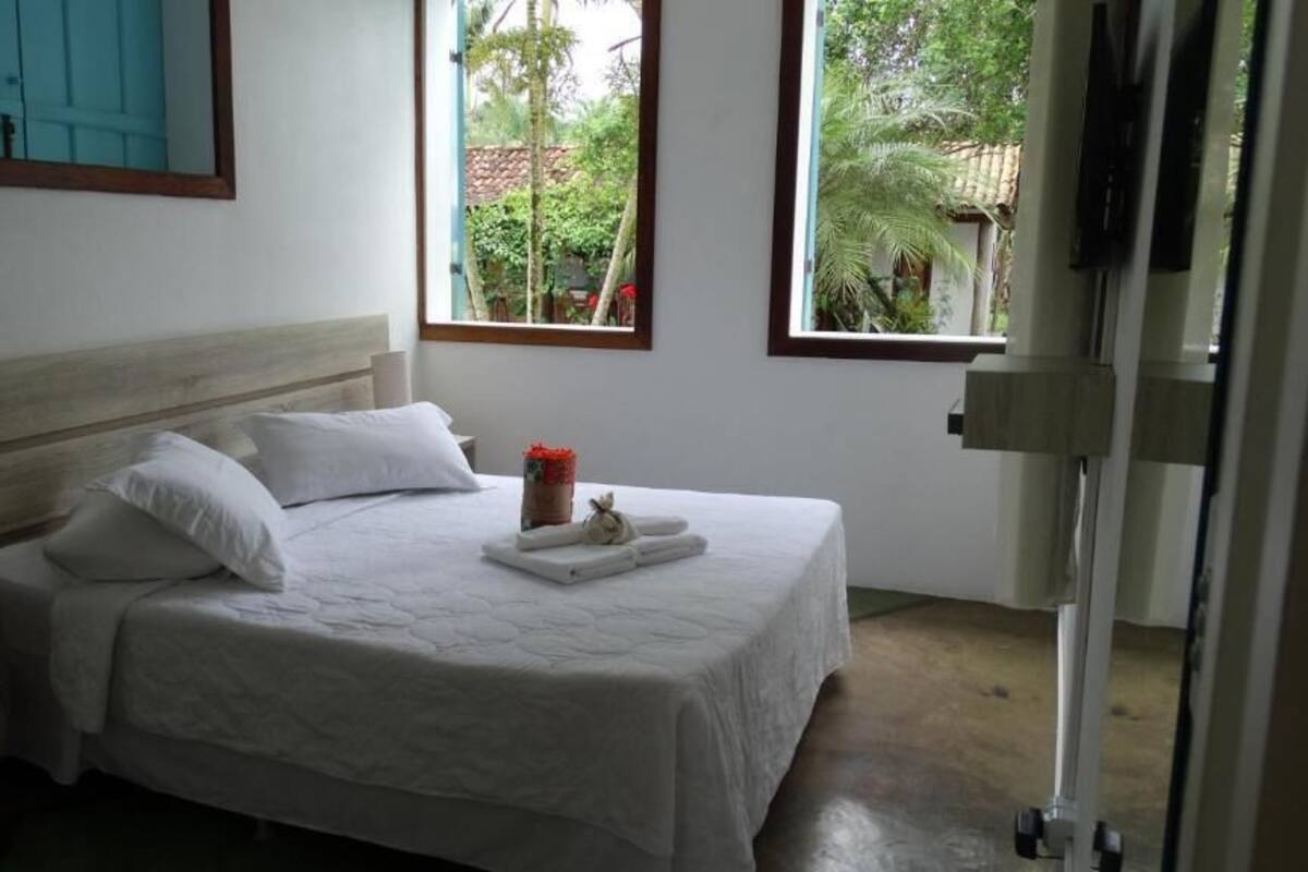 A bedroom with a bed, a nightstand, a window, and a door.