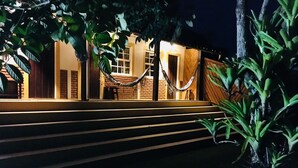 A building with a brick facade, a wooden staircase, and a hammock hanging between two windows. - Pouso Atobá (Paraty)