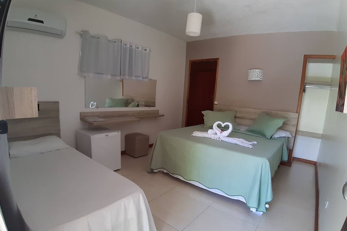 A hotel room with two beds, a small desk, a refrigerator, and a window with curtains.