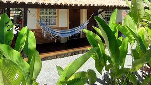 A two-story building with a balcony, a hammock, and tropical plants. - Pouso Atobá (Paraty)