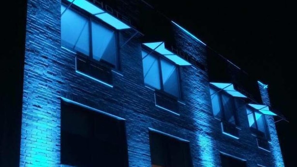 Un edificio de varios pisos con iluminación azul que resalta los bordes de las ventanas y paredes.