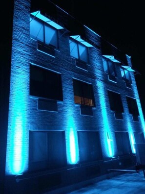 A multi-story building with illuminated blue lighting along the edges of the windows and walls. - Hotel Key LaGuardia Airport (Flushing)