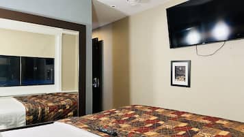 A hotel room with two beds, a large window, a flat-screen TV mounted on the wall, and a framed picture on the wall.