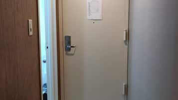 Um corredor com piso coberto por carpete, uma porta com interruptor de luz e um porta-roupas fixado na parede com ganchos.