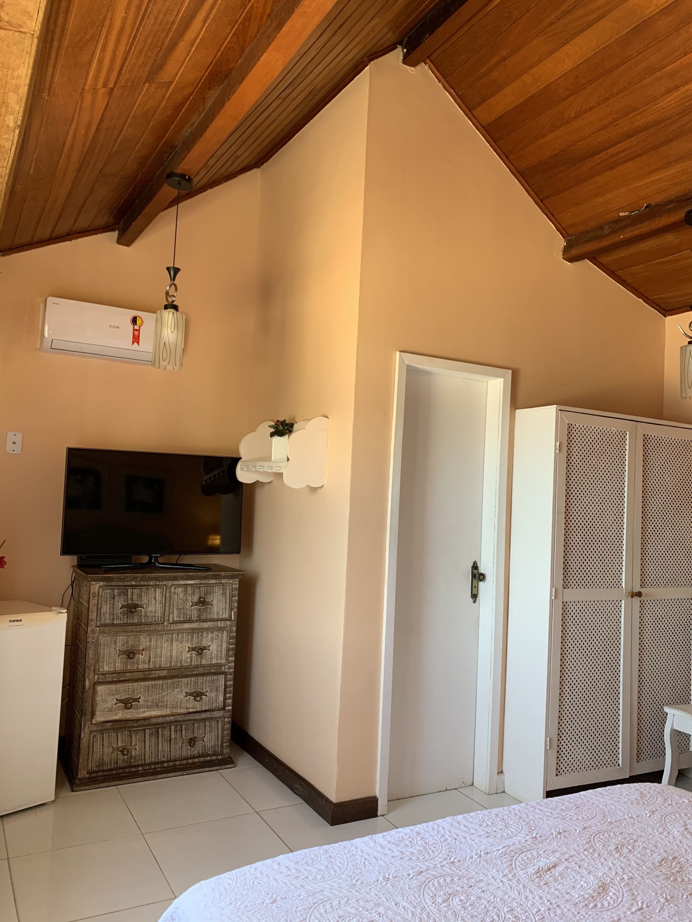 Une chambre à coucher comprenant un lit, une commode, un téléviseur, un climatiseur et une armoire.
