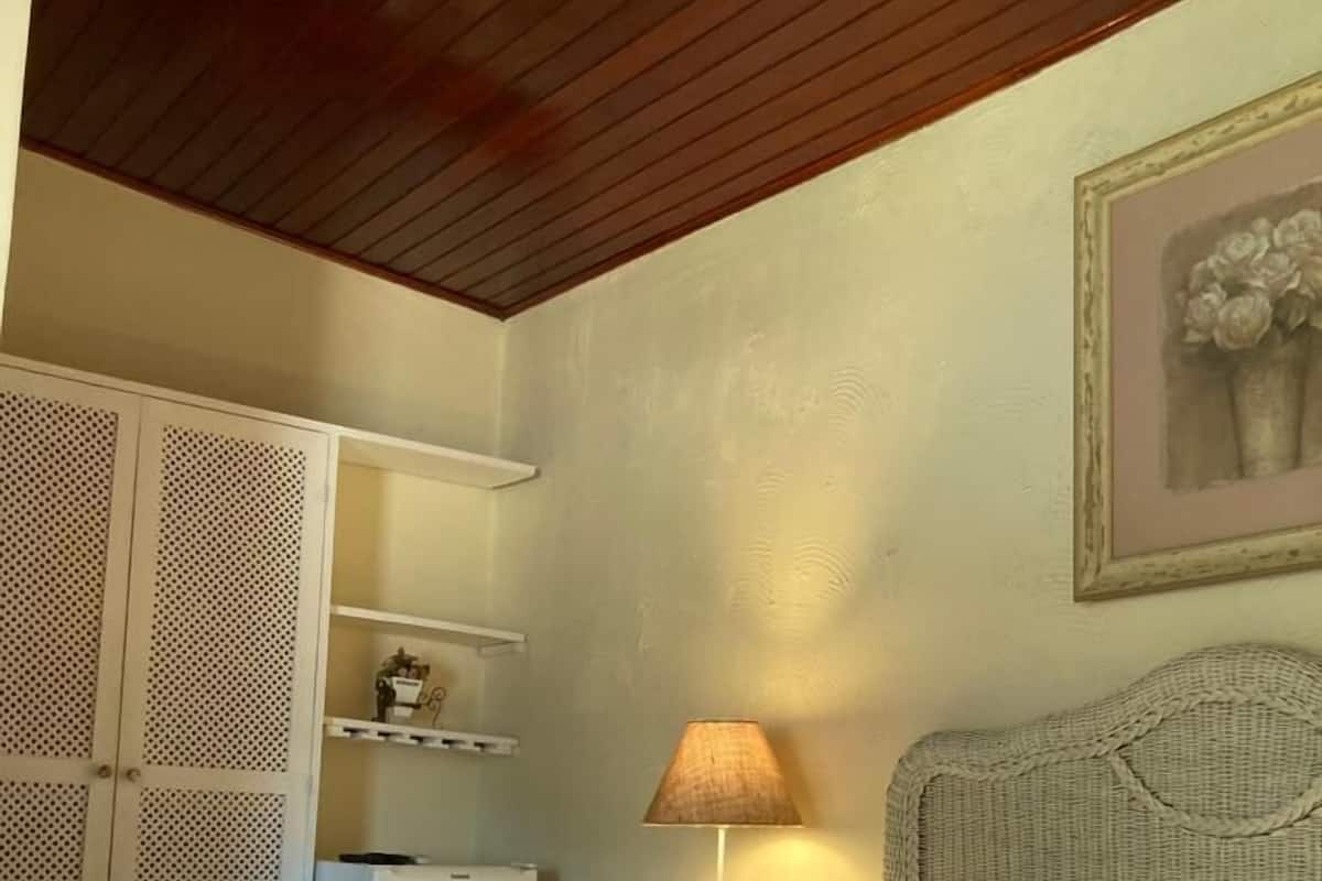A bedroom with a bed, a nightstand, a lamp, a wardrobe, and a framed picture on the wall.