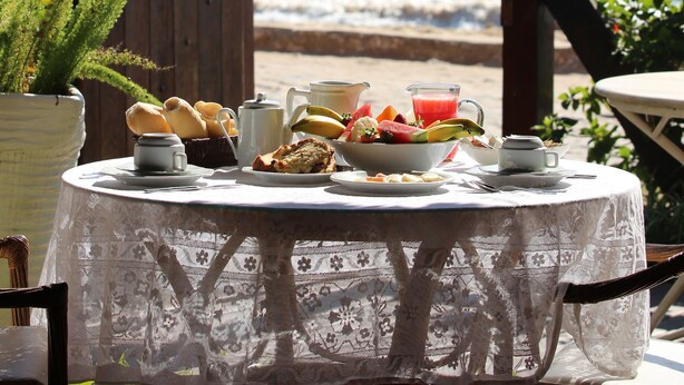 Una mesa dispuesta para el desayuno con vista al mar y una isla boscosa.
