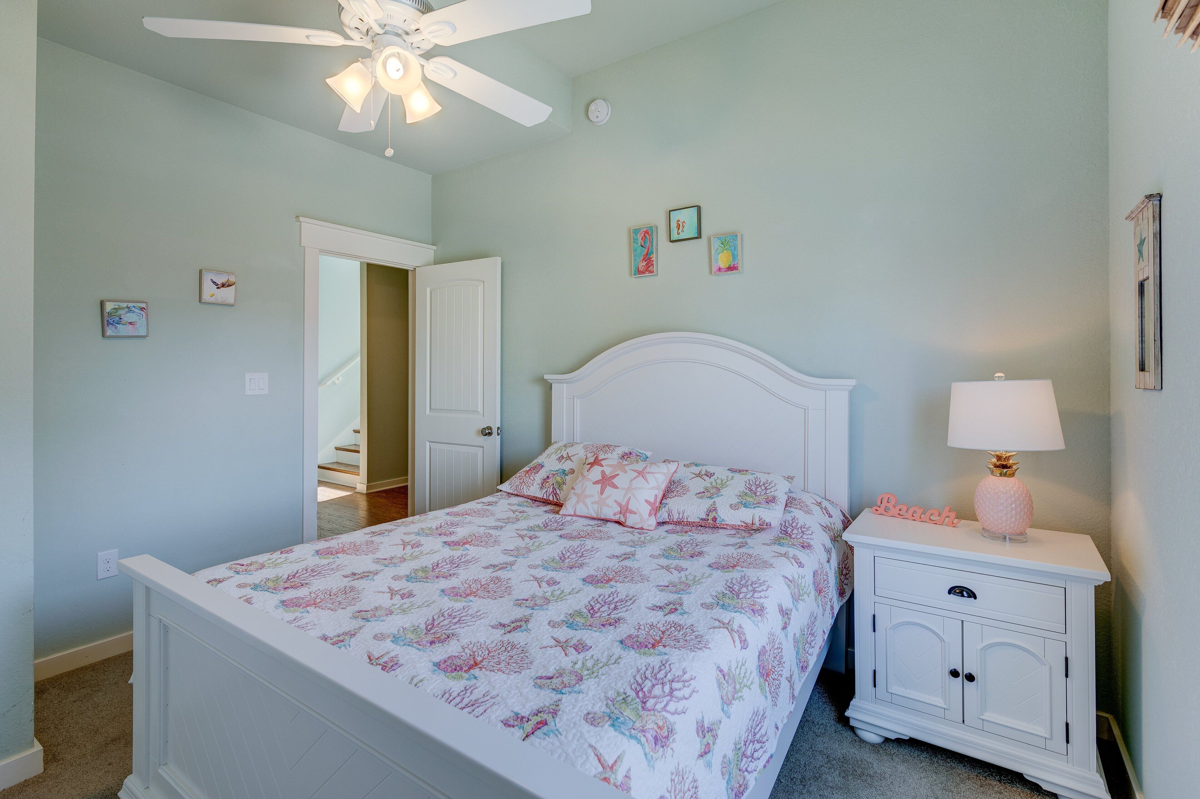 Un dormitorio con cama, mesita de noche, ventilador de techo y decoración en la pared.
