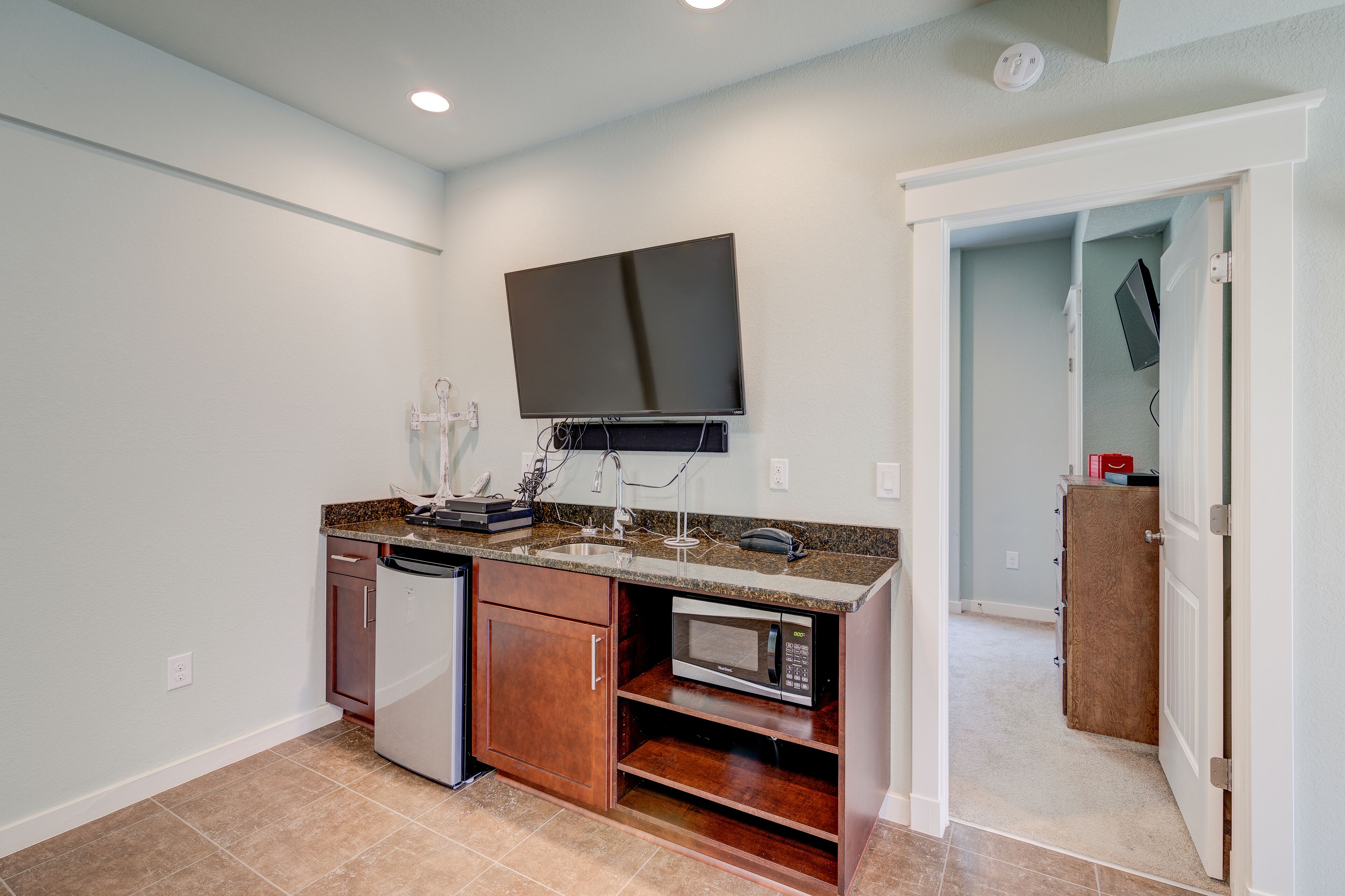 A compact kitchen with a built-in microwave, a dishwasher, and a flat-screen TV mounted above the counter.