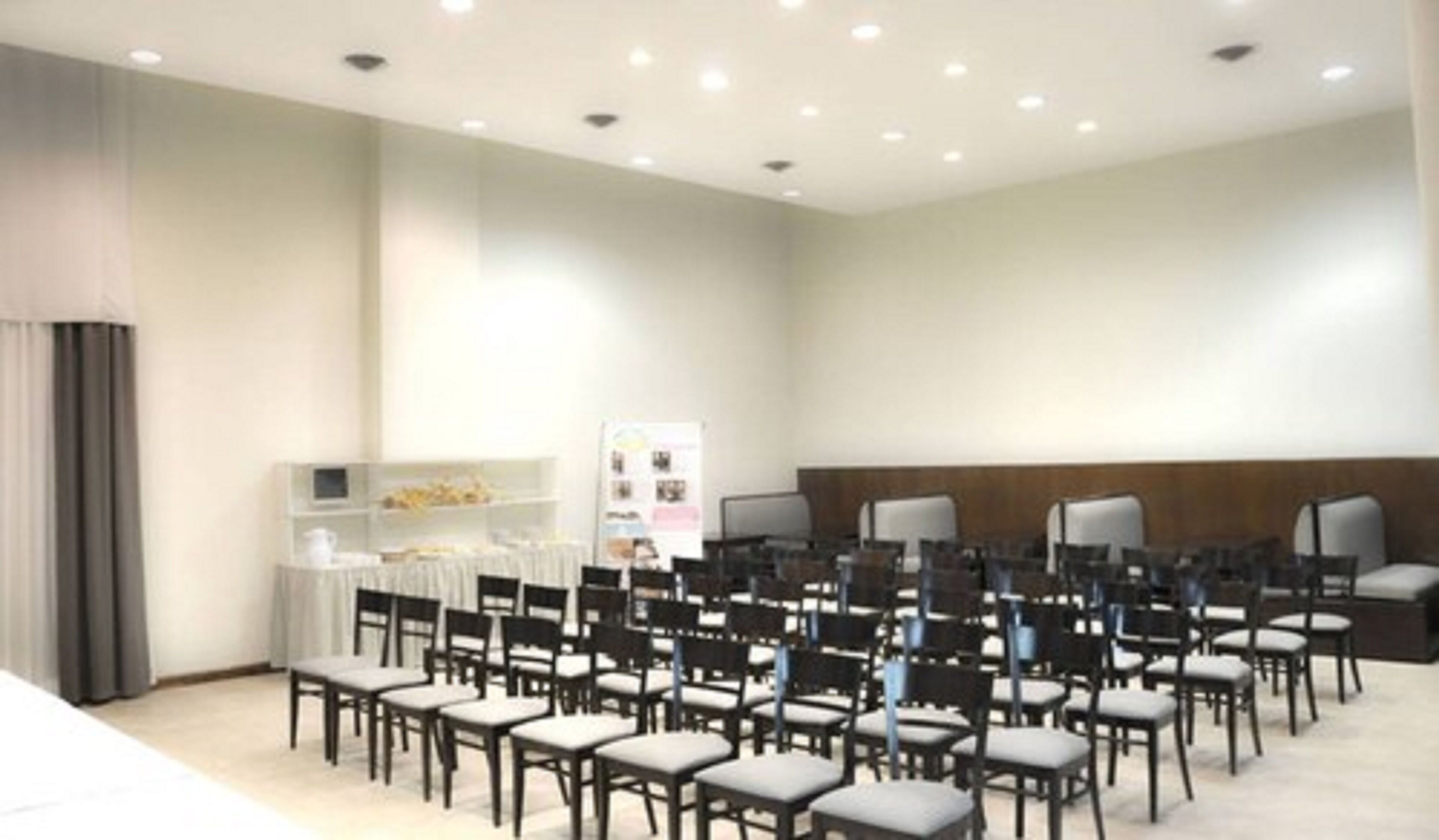 Une salle de conférence avec des rangées de chaises, un tableau blanc et une petite table sur laquelle se trouve un ordinateur portable.