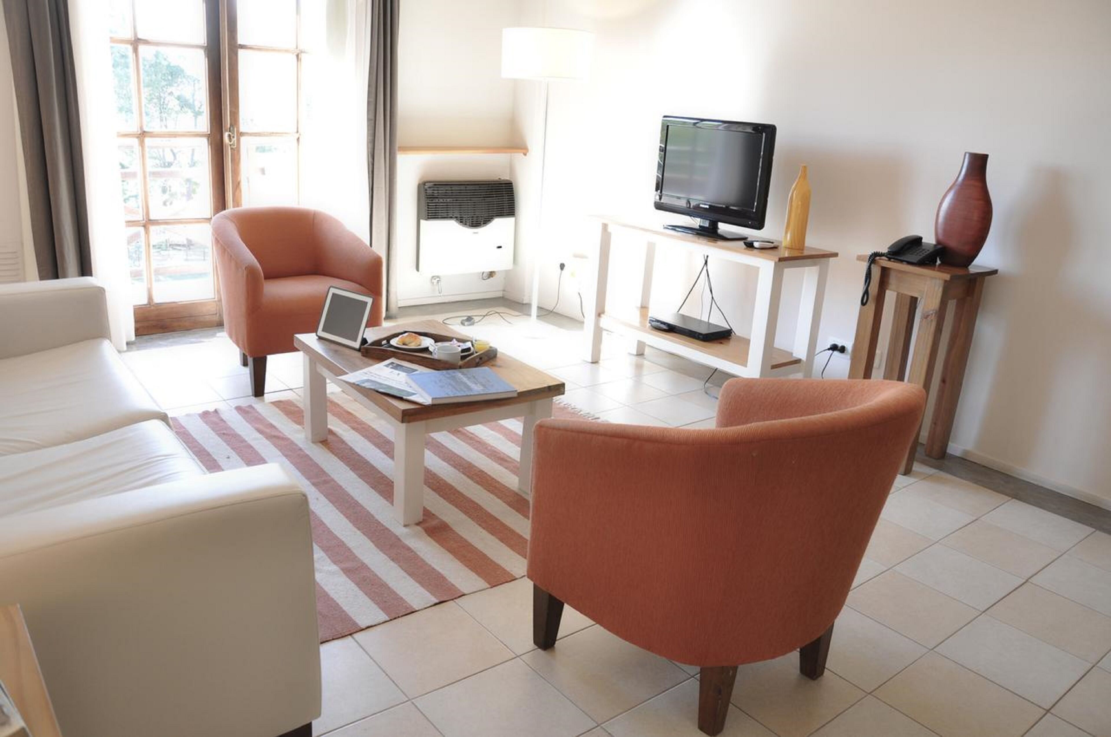 Una sala de estar con sofá, sillón, mesa de centro, televisor y lámpara.
