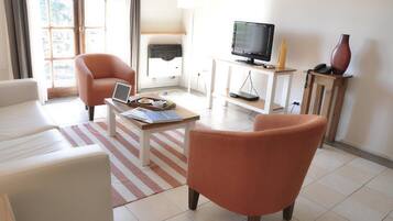 Una sala de estar con sofá, sillón, mesa de centro, televisor y lámpara.