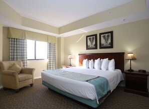 Relax in comfort with a large bed, two nightstands, and a chair, surrounded by framed artwork.