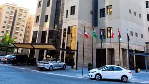 A modern hotel building with multiple floors, a prominent 'HOTEL' sign, and several flags in front. - Rihanna Hotel (Salmiya)