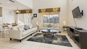 A modern living room with a sofa, coffee table, and TV stand. - Palm Key Villa by VillaDirect (Kissimmee)