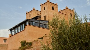 A building with a modern glass extension and traditional brick towers. - Kasbah Flilou (Ait Sedrate Jbel El Soufla)