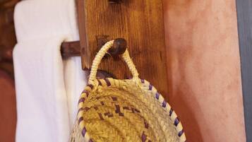 A woven basket hanging on a wooden wall-mounted rack, with a towel hanging below it.