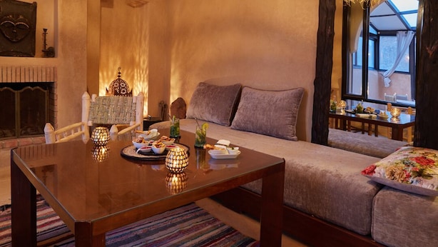 A cozy living room with a sofa, a wooden coffee table, and a fireplace. - Kasbah Flilou (Ait Sedrate Jbel El Soufla)