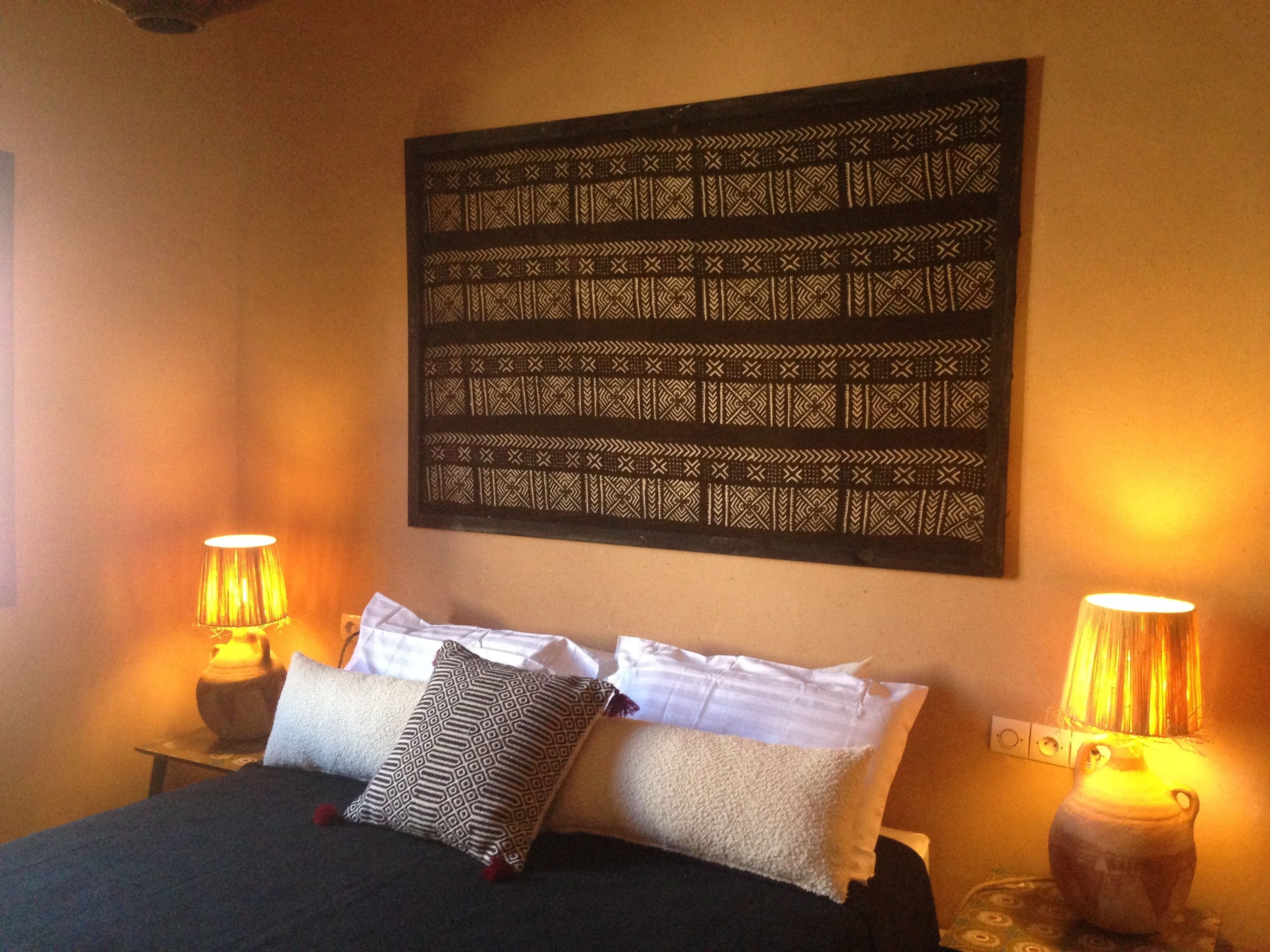 Une chambre à coucher avec un lit, deux lampes de chevet et une décoration murale.