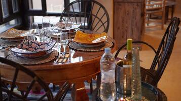 Una mesa de comedor dispuesta con platos tradicionales marroquíes, vasos y una botella de agua.