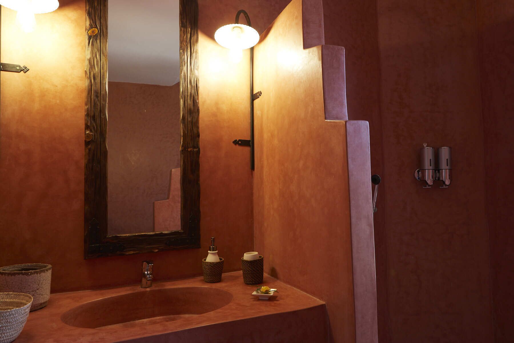 Un baño con tocador de madera, un espejo grande, un lavamanos y un perchero para toallas.