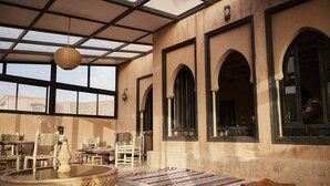 A spacious room with large windows, a central fountain, and traditional furniture. - Kasbah Flilou (Ait Sedrate Jbel El Soufla)