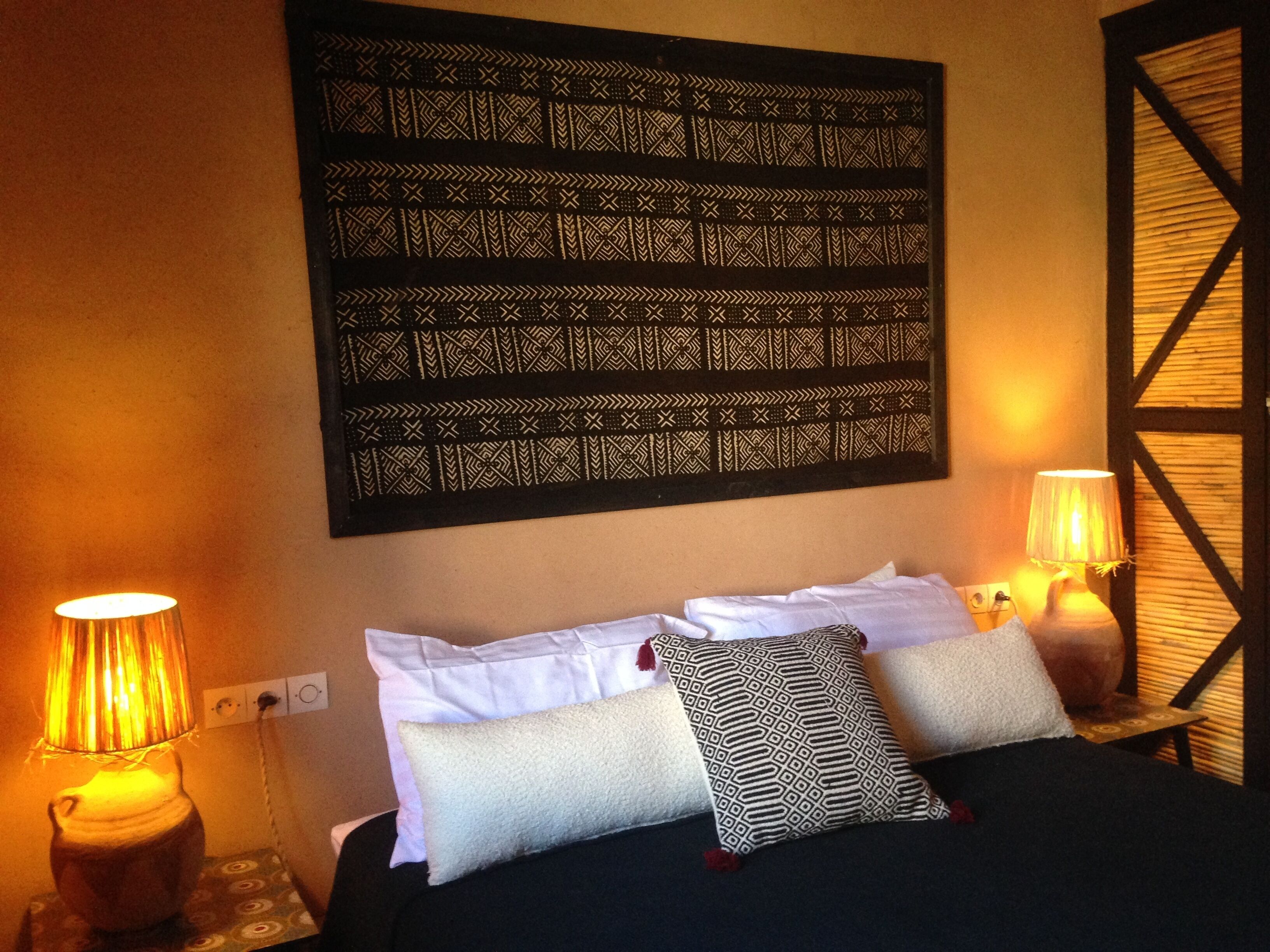 A hotel room with a large bed, two bedside lamps, and a decorative wall hanging.