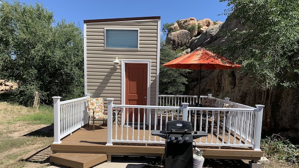 Un petit bâtiment d’un seul étage, doté d’une terrasse, d’un barbecue et d’un parasol.