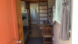 Un espace de vie compact et ouvert, comprenant un lit en mezzanine, un coin repas avec une table et des chaises, et une petite cuisine.