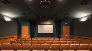 Ein Theater mit Sitzreihen, einer großen Leinwand und einem Projektor.