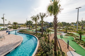 A swimming pool with a surrounding deck, palm trees, and a water slide.