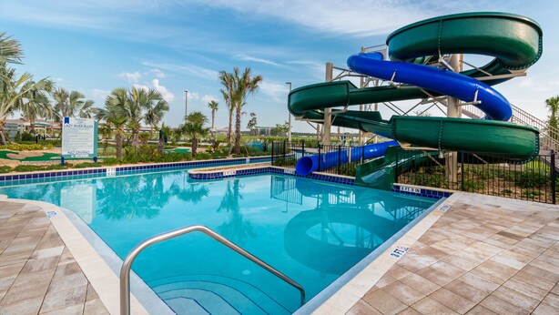 Una piscina con tobogán y palmeras al fondo.