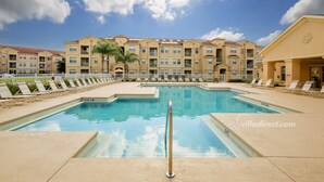 A swimming pool with a 3 FT 6 IN depth, surrounded by lounge chairs and a building with multiple balconies. - Cresent Moon by VillaDirect (Davenport)
