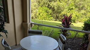 A round table with white chairs on a balcony with a view of a green garden. - Cresent Moon by VillaDirect (Davenport)
