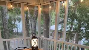 A covered patio with a wooden table, teal chairs, and a lantern.