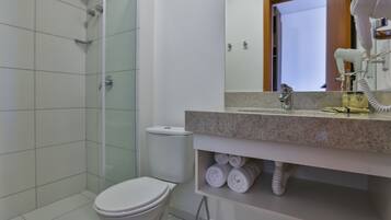 A bathroom with a shower, toilet, and a vanity with towels.