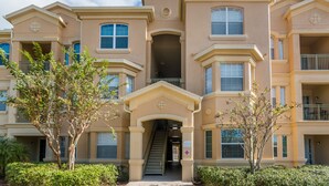 A multi-story building with a central entrance, balconies, and a staircase leading to the upper floors. - Disneys Den by VillaDirect (Davenport)