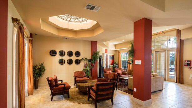 A lobby with a high ceiling, a skylight, and a seating area with multiple chairs and a coffee table. - Disneys Den by VillaDirect (Davenport)