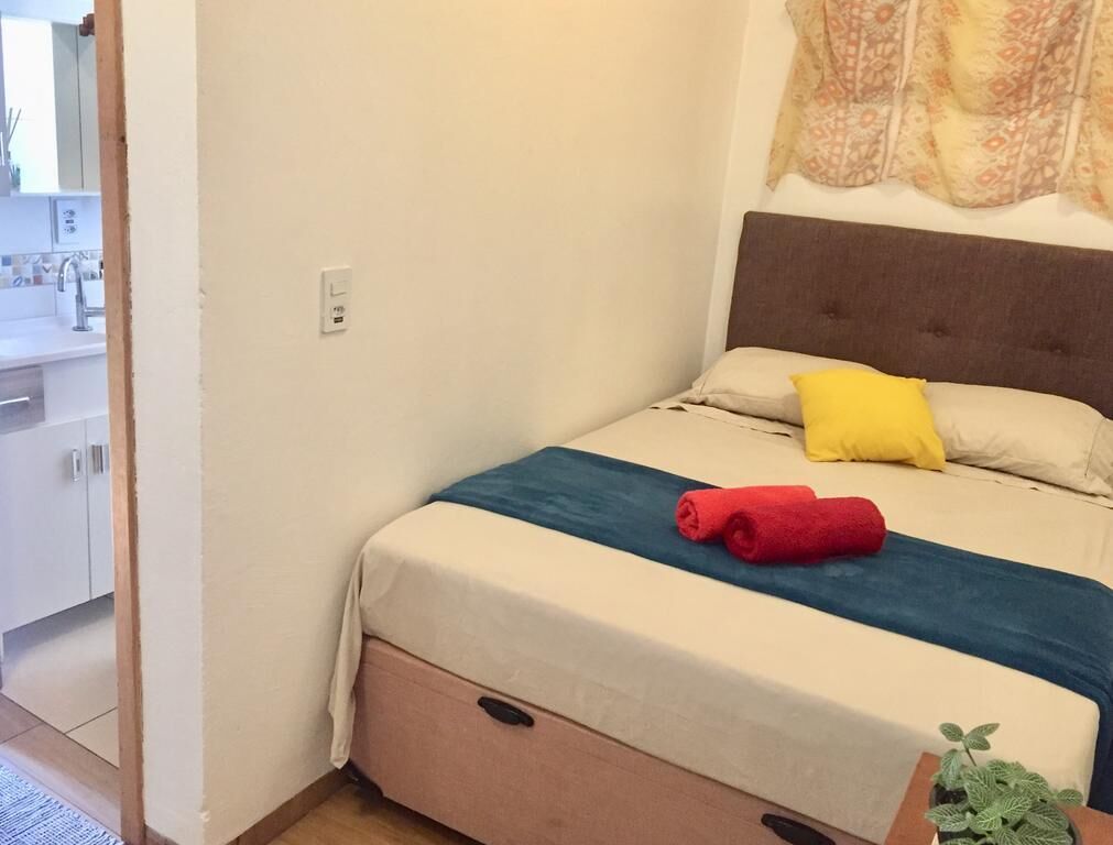 Un dormitorio con una cama, una mesita de noche, una ventana y vistas al baño.