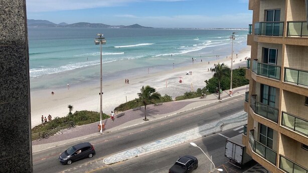 Blick auf einen Strand vom Gebäude aus, im Vordergrund eine Straße.