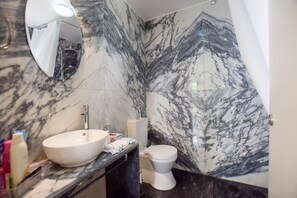 Un baño con lavamanos, inodoro y espejo de mármol.