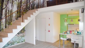 A modern interior with a staircase, a kitchen area with green cabinets, and a dining bar with stools. - Tia Malaca (Sintra)